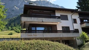 A modern two-story building with a balcony, named "Valetta Sura," set against a mountainous backdrop. - Valetta Sura by Interhome (Flims)