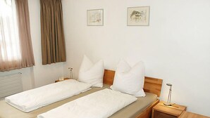 A double bed with white linens, a wooden headboard, two bedside tables, and a floor lamp. - Valetta Sura by Interhome (Flims)