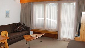 A cozy living room with a brown sofa, a wooden table, and a bench. - Valetta Sura by Interhome (Flims)