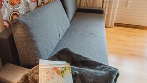 Un divano grigio con una coperta nera e un libro intitolato 'POPCULT'.