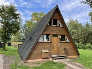 A wooden A-frame cabin with a front porch and a small deck. - Geesthof by Interhome (Hechthausen)
