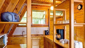 Het interieur van een houten blokhut met een keukenhoek, inclusief een spoelbak, fornuis en koffiezetapparaat.