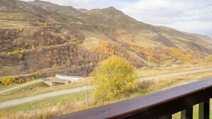 Vista panorámica de un paisaje montañoso con carretera, puente y árboles de follaje otoñal.