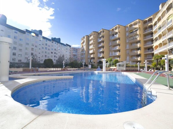 Una piscina rodeada de edificios residenciales de varios pisos con balcones.