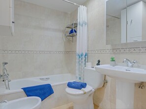 Un baño con bañera, inodoro, lavamanos y ducha.