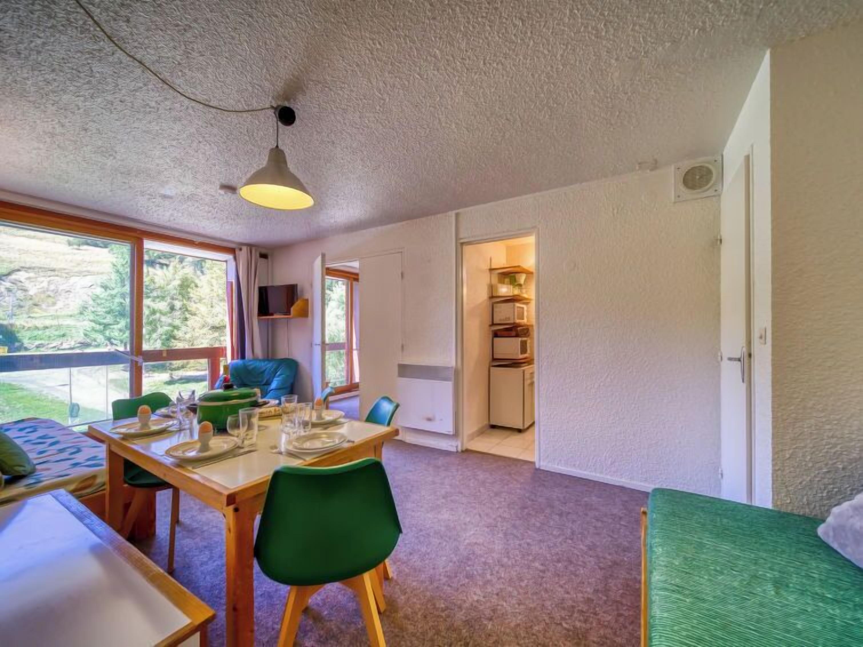 Una habitación acogedora con una mesa de comedor lista para cuatro personas, un sofá verde y una cama.