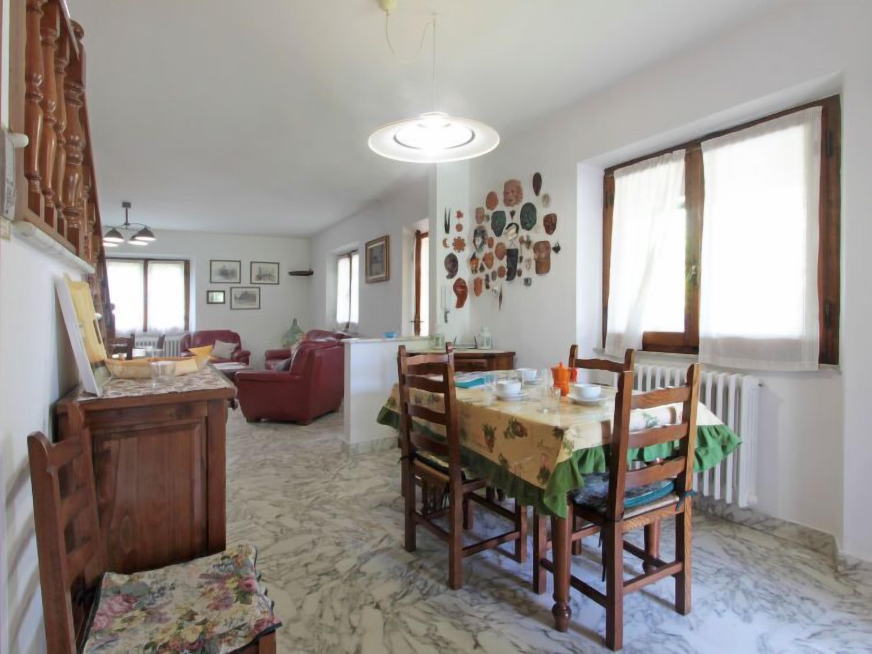 A dining area with a marble floor, wooden furniture, and a wall decorated with various items.