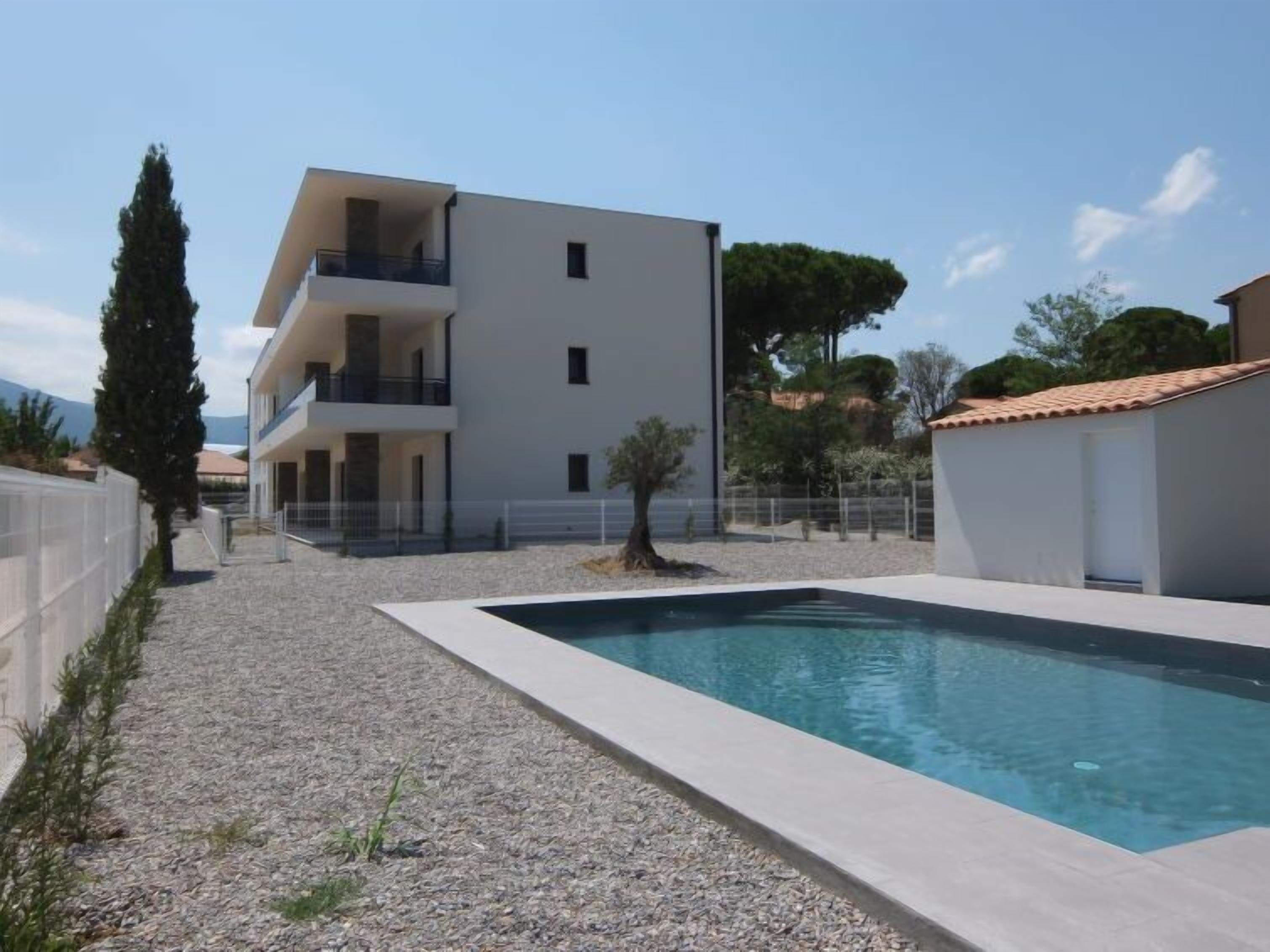 Un edificio moderno a due piani con una piscina in primo piano.