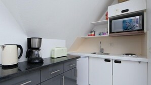 Eine kompakte Küchenzeile mit Kaffeemaschine, Toaster, Mikrowelle und Spüle.