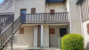 Ein zweistöckiges Gebäude mit Balkon, Treppe und einem kleinen Garten.