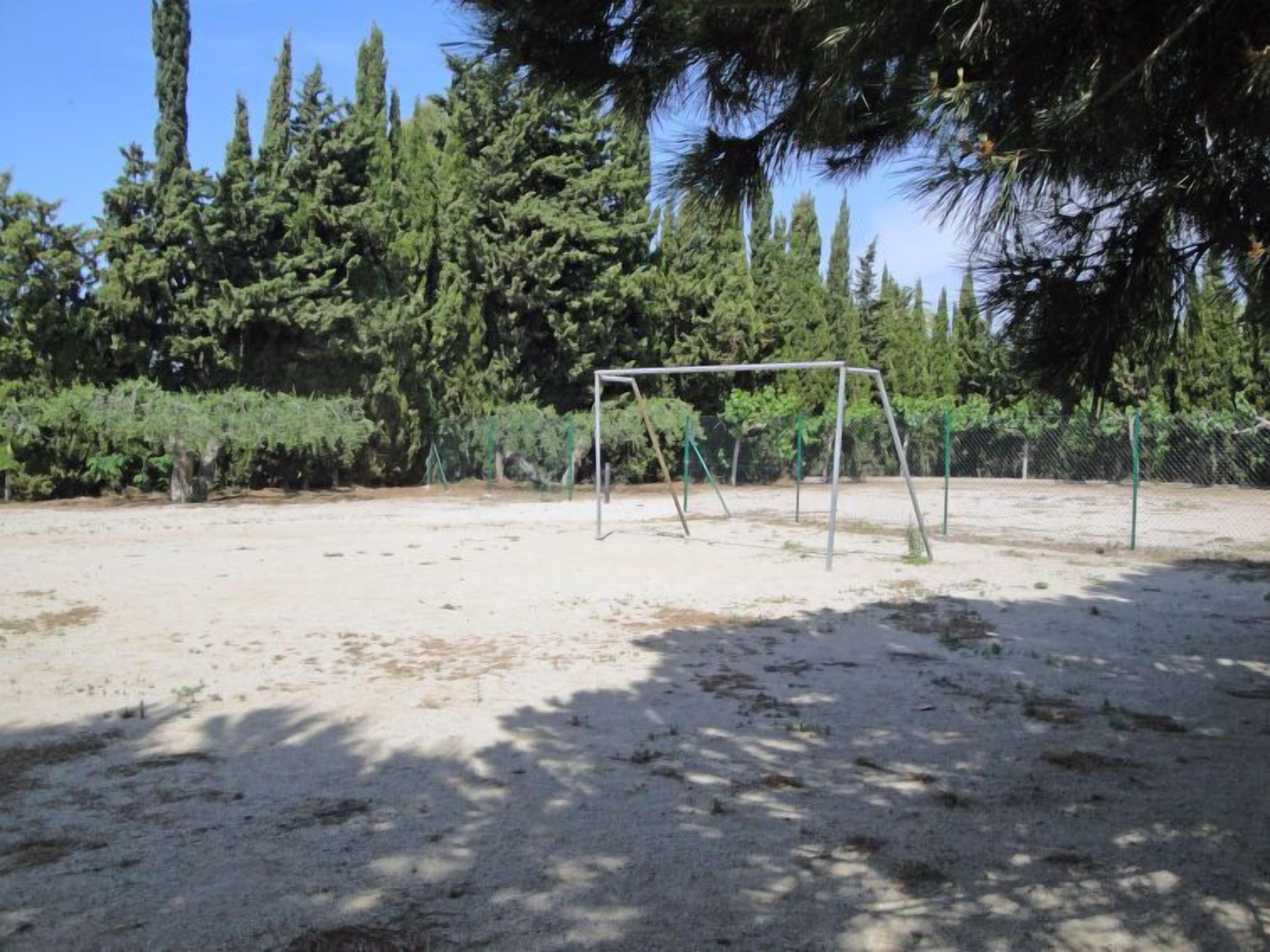 Zona d'exterior amb sorra i un tobogan metàl·lic.
