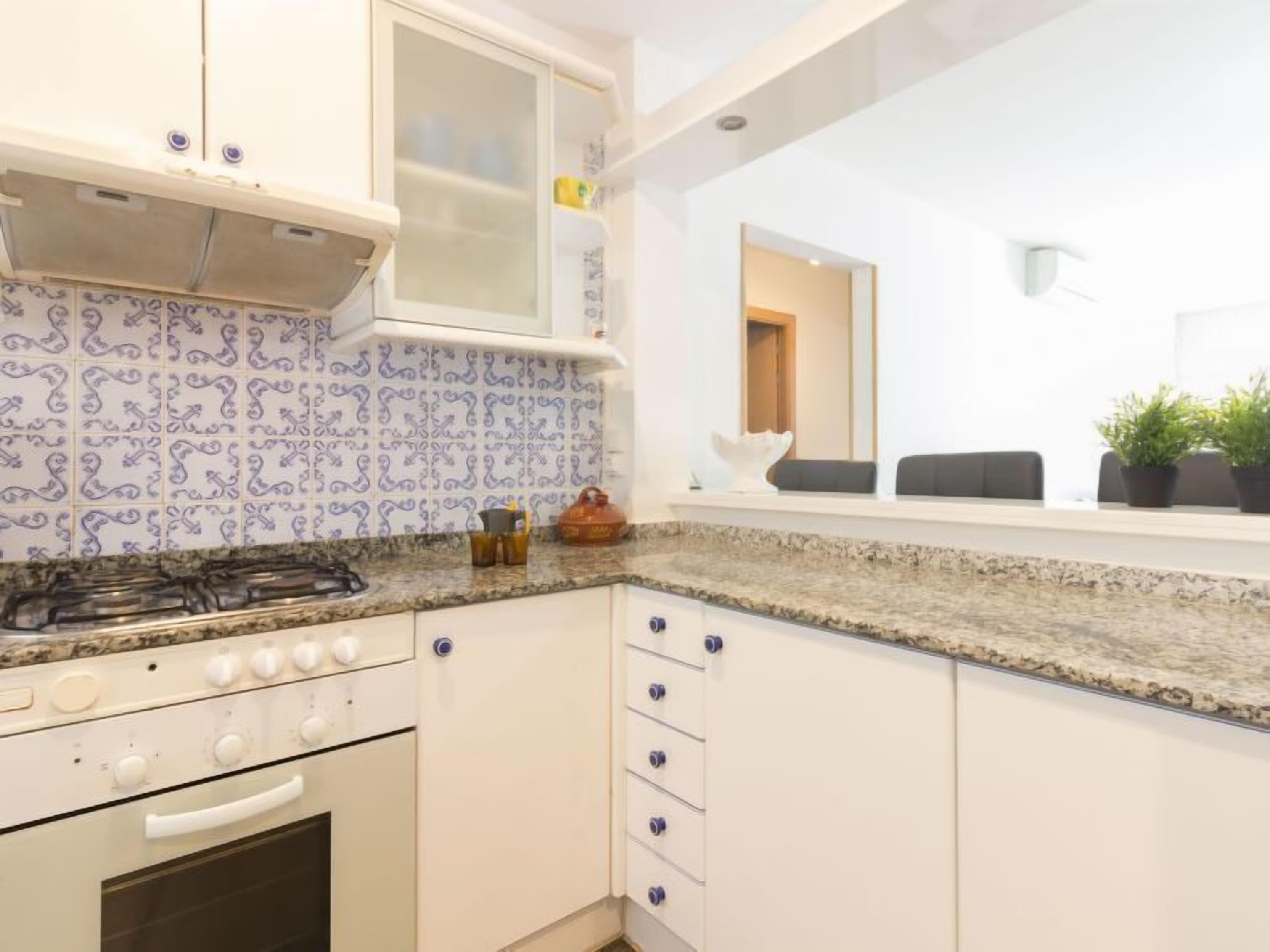 A modern kitchen with white cabinets, a granite countertop, and a built-in stove.