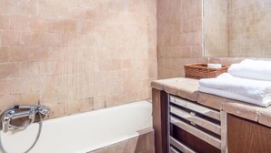 Ein Badezimmer mit einer Badewanne, einem Holzbadezimmer-Möbelset und einem Spiegel.