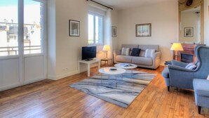 Una sala de estar con sofá, sillón, televisor y chimenea.