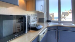 Una cocina moderna con microondas integrado, extractor de humos y ventana con vistas a edificios.