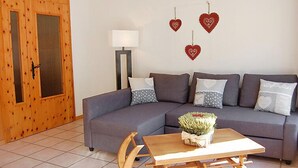 Una sala de estar con un sofá gris, una mesa de centro de madera y una lámpara.