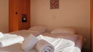 Habitación de hotel con dos camas, cabecero de madera, un pequeño adorno en la pared y un enchufe.