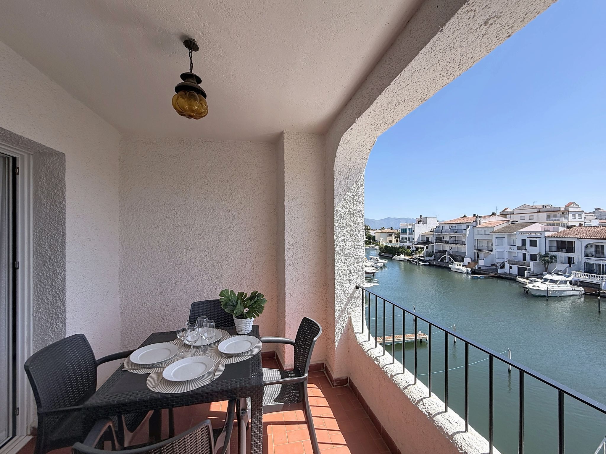 A balcony with a table set for dining, overlooking a marina with boats and buildings.
