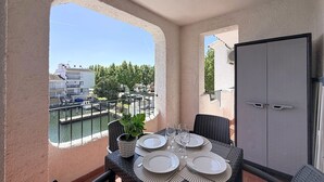 A balcony with a table set for four, a potted plant, and a view of a marina. - Port Banyuls by Interhome (Empuriabrava)