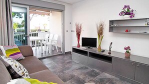 A modern living room with a sofa, TV, and decorative items. - Apartment DMS V by Interhome (Cambrils)