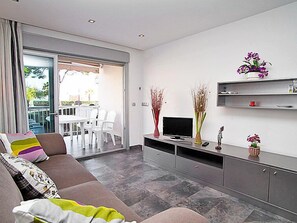 Sala de estar moderna com sofá, TV e objetos decorativos.