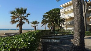 A beachfront hotel with palm trees, a clear sky, and a view of the sea. - Apartment DMS V by Interhome (Cambrils)