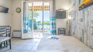 Camera d'albergo con un letto, una televisione, una finestra con tende, un tavolino e una sedia.