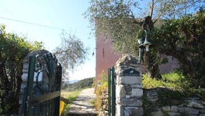 Un camí de pedra que condueix a una porta amb un cartell que diu "CA E O SAITE".