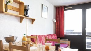 Ein Essbereich mit Holztisch, Stühlen, einer Kaffeemaschine und Frühstücksangeboten.
