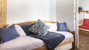 Ein gemütliches Zimmer mit einem hölzernen Bett, einer kleinen Couch und einer Kaffeemaschine auf einem Regal.