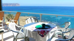 A balcony with a table set for two, overlooking a beach and the sea. - Golden Life by Interhome (Jávea)