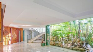 A spacious indoor area with a polished floor, a staircase, and a large glass wall featuring a tropical garden view. - Golden Life by Interhome (Jávea)