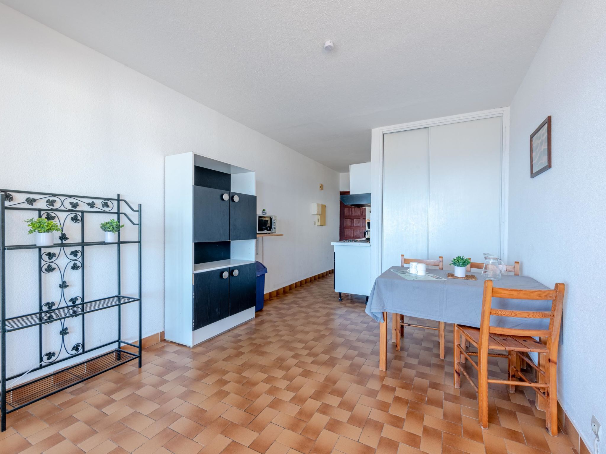 Cocina compacta con comedor, suelo de baldosas, placa de cocina integrada y un refrigerador pequeño.
