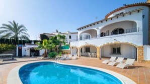 A swimming pool surrounded by a white building with multiple balconies and a patio area with lounge chairs. - Vacation home Luisa by Interhome (Calpe/Calp)