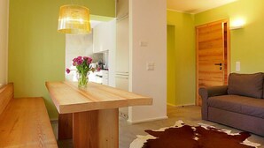 A modern living room with a wooden bench, a cowhide rug, a sofa, and a dining table with a vase of flowers. - Chesa La Soliva by Interhome (St. Moritz)