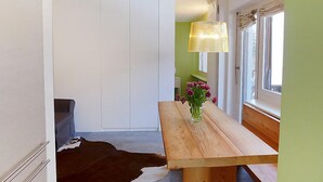 A modern kitchen with a wooden table, a hanging lamp, and a vase with flowers. - Chesa La Soliva by Interhome (St. Moritz)