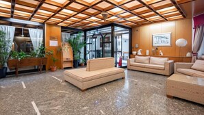 Eine Lobby mit Holzbalkendecke, einer Rezeption, einer Sitzecke und einem großen Fenster.