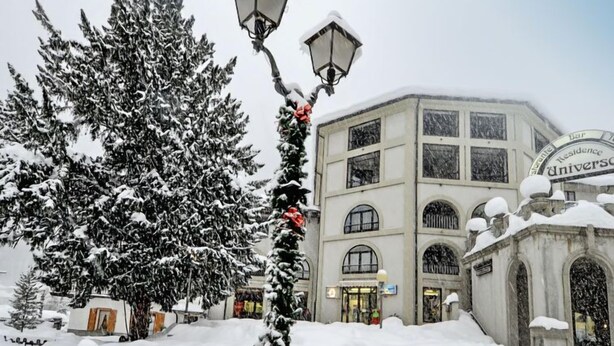 Ein Gebäude mit einem Schild, auf dem „Residence Universale“ steht, inmitten verschneiter Landschaft.