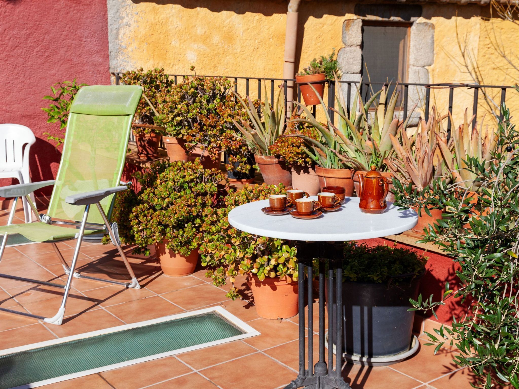 A patio with a round table, chairs, and potted plants.