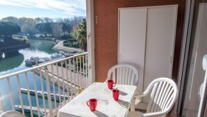 Een balkon met een tafel en stoelen, uitkijkend op een wateroppervlak met boten.