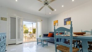 A spacious living area with a dining table, blue chairs, a sofa, and a ceiling fan. - Gladiols by Interhome (Cambrils)
