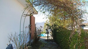 A stone pathway leading to a building with a white exterior and a brick chimney. - Vacation home Ursula by Interhome (Pugerna)