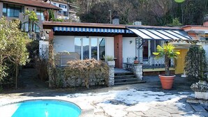 A two-story house with a swimming pool, stone steps, and potted plants. - Vacation home Ursula by Interhome (Pugerna)