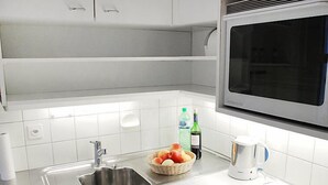 A modern kitchen with a stainless steel sink, a microwave, and a basket of fruit. - Vacation home Ursula by Interhome (Pugerna)