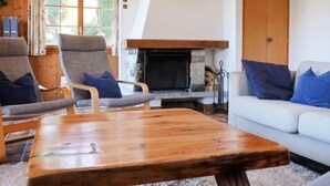 Een gezellige woonkamer met een open haard, houten meubels en een witte bank.