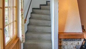 Een trap met een houten leuning en een stenen muur met een open haard.