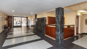 Un hall d’entrée spacieux comprenant un comptoir d’enregistrement, un bureau d’accueil et un espace détente avec des bancs.