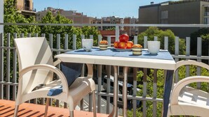 Un balcon avec une table préparée pour le petit-déjeuner, avec des pommes, des viennoiseries et une tasse.