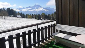 A balcony with a view of snow-covered mountains and a wooden cabin. - Marignac 33 by Interhome (Villars)