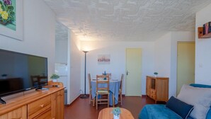 Un soggiorno accogliente con televisione, arredi in legno, un divano blu e un'area pranzo con sedie e tavolo.
